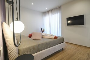 A modern bedroom with a bed, a flat-screen TV, and a bedside table. - COBALTO Room- Aurisea Luxury Stays (Bari)