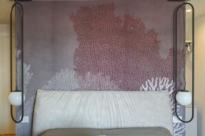 A bed with a grey mattress and white pillows, a wall with a red and white coral pattern, and two black floor lamps. - COBALTO Room- Aurisea Luxury Stays (Bari)