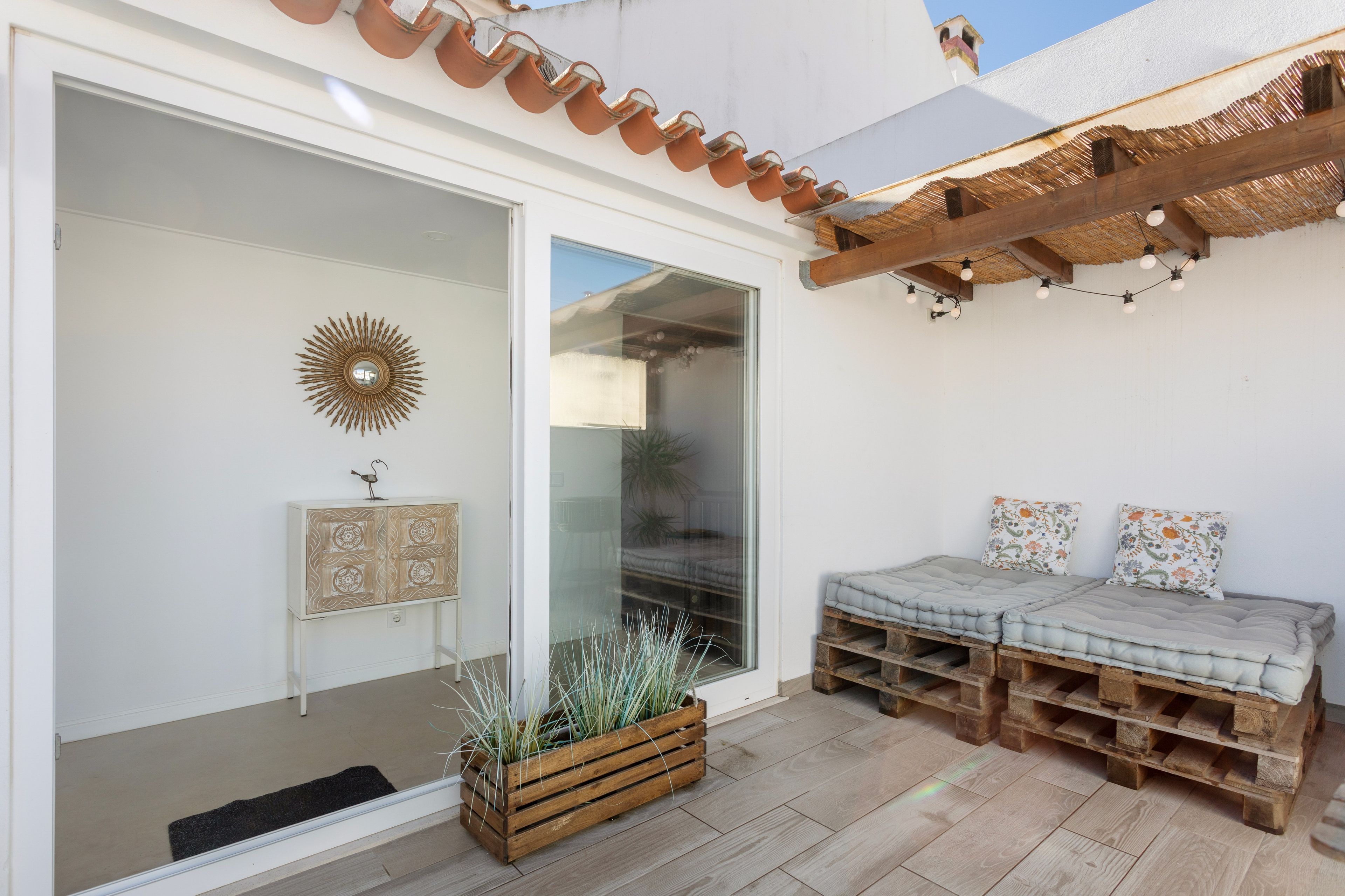 A patio with a wooden bench, a potted plant, and a decorative mirror.