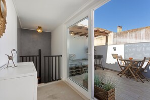 Quarto com cama, uma mesinha, uma cadeira, janela e vista para o exterior.