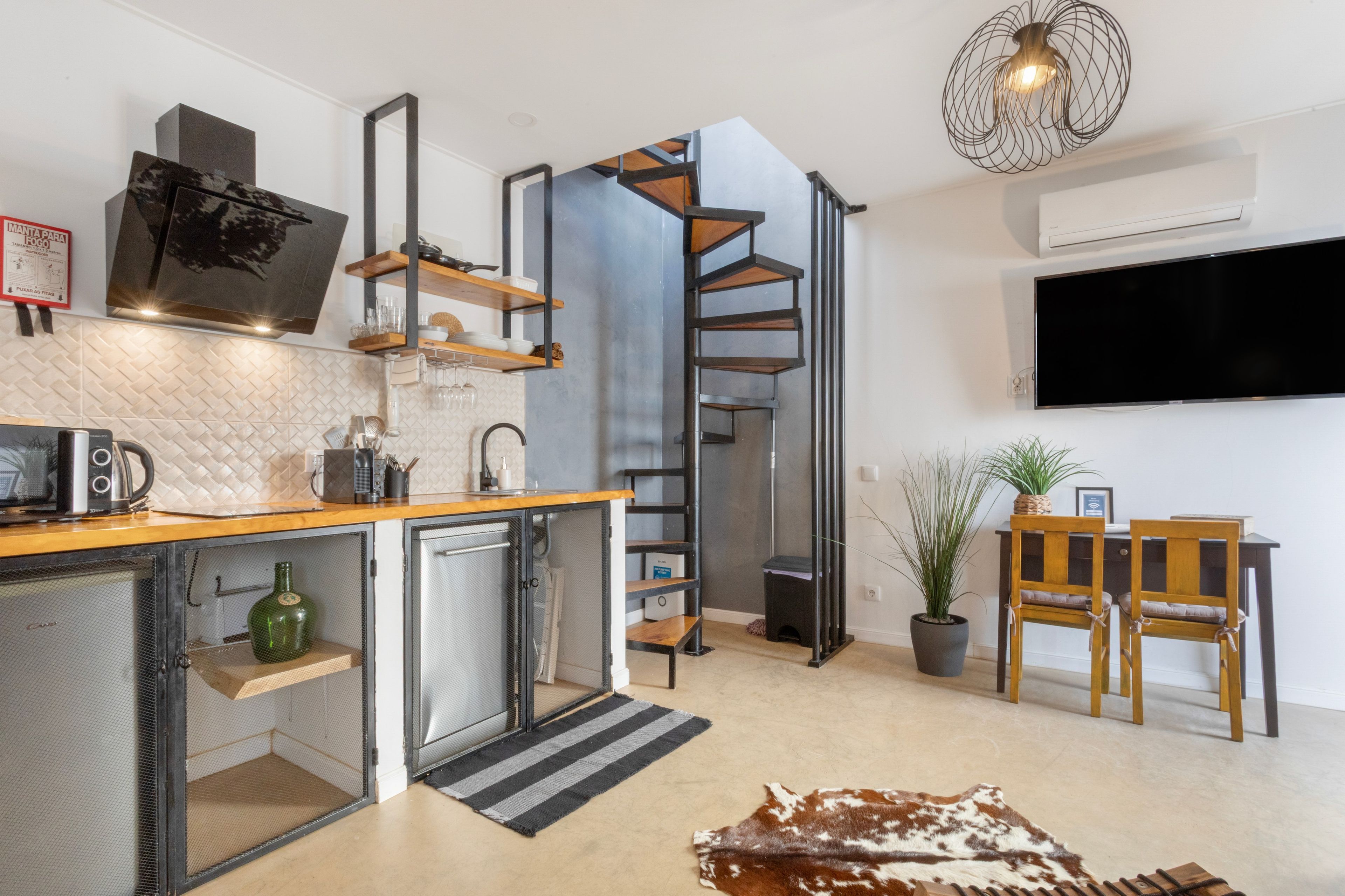 A compact kitchen with a microwave, toaster, and coffee maker, a small refrigerator, and a built-in oven.