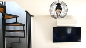 Un interno moderno con una scala a chiocciola, un televisore a schermo piatto, una scrivania con sedie e una pianta in vaso.