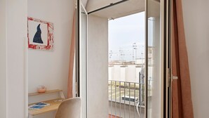 A balcony with a view of buildings and a street, a chair, a small table with a bowl, and a framed picture on the wall. - Le Stanze In Centro – Standard Double Room (Naples)