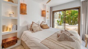 Ein modernes Schlafzimmer mit einem großen Bett, Einbauschränken und Blick auf einen üppigen Garten.