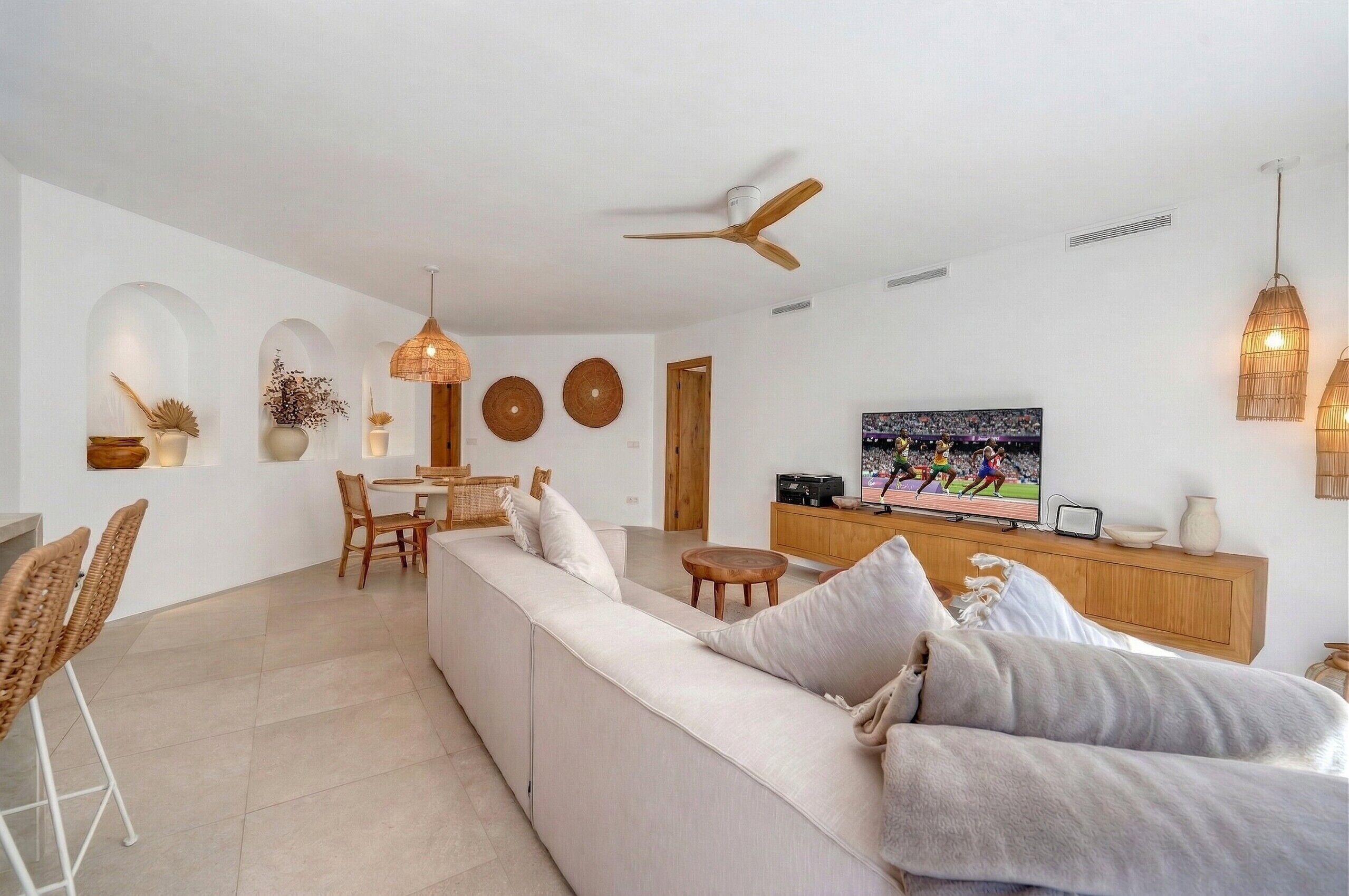 A modern living room with a sofa, dining area, and TV.