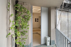 A hallway with a plant, a door leading to a room, and a staircase. - Le Stanze In Centro - Standard Double Room (Naples)