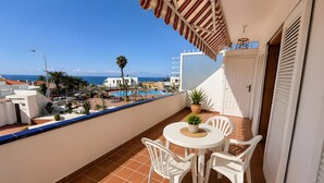 A balcony with a view of the sea, a pool, and a white door. - Vacation Apartment 'Maika's' with Sea View, Shared Pool and Wi-Fi (Costa Adeje)