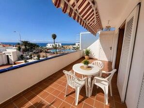 Een balkon met uitzicht op zee, een zwembad en een witte deur.