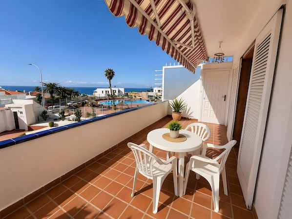 Un balcon avec vue sur la mer, une piscine et une porte blanche.