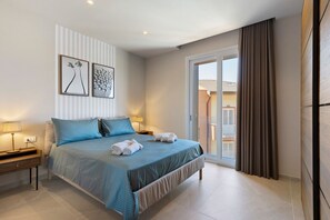 Habitación de hotel moderna con una cama grande, dos mesitas de noche y vistas al exterior.