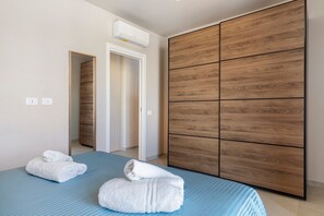Une chambre d’hôtel avec un lit, une armoire en bois et une salle de bain visible à travers une porte ouverte.