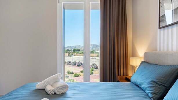 Une chambre d’hôtel avec un lit, une vue sur l’extérieur, une fenêtre avec des rideaux et une lampe sur la table de chevet.