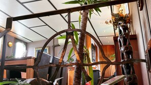 Una habitación con una planta en maceta grande, una cafetera y una estructura decorativa de metal.