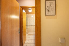 A wooden door leading to a bathroom with a tiled floor and a shower area.