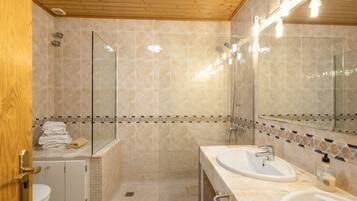 Een badkamer met een douche, een wastafel, een toilet en een spiegel.