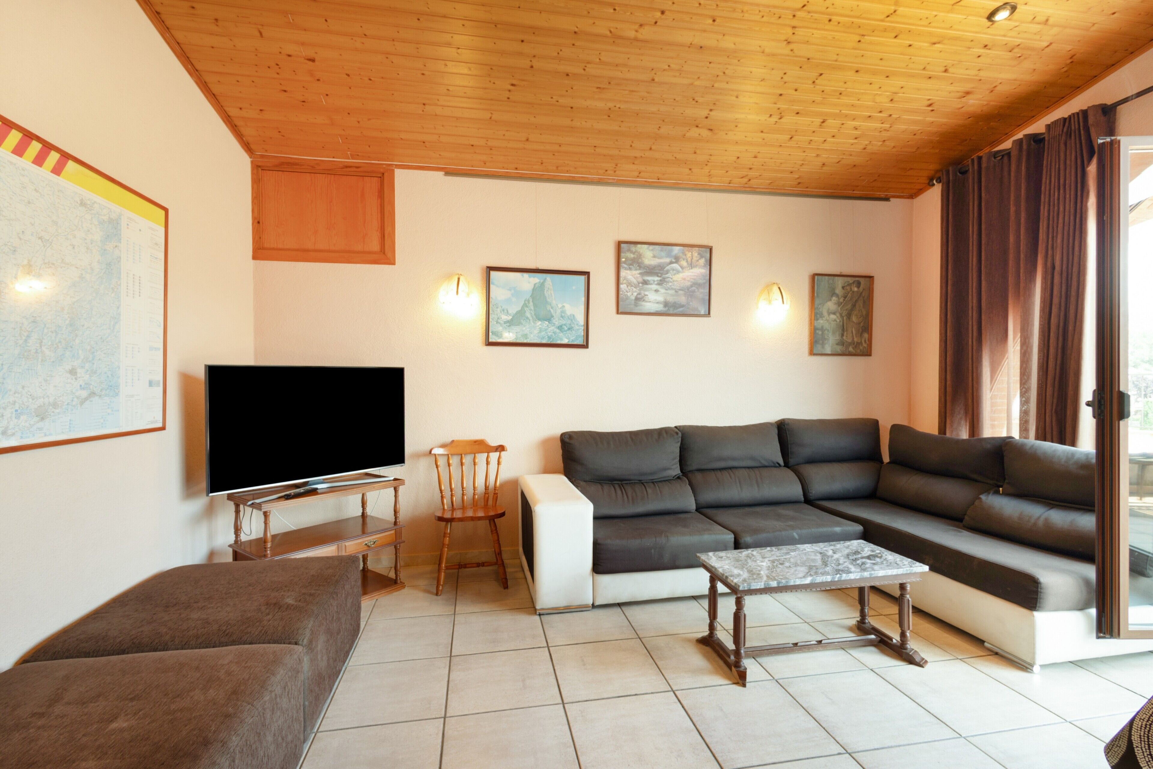 Un soggiorno con una televisione a schermo piatto, un divano, un tavolino da caffè e un soffitto in legno.