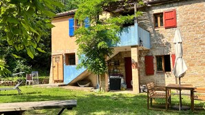 Un edificio rústico con fachada de piedra, terraza de madera y zona de estar exterior cubierta.