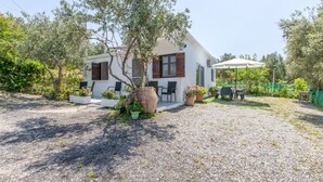 Edifici blanc amb un camí de grava, seients a l'exterior i plantes en testos.