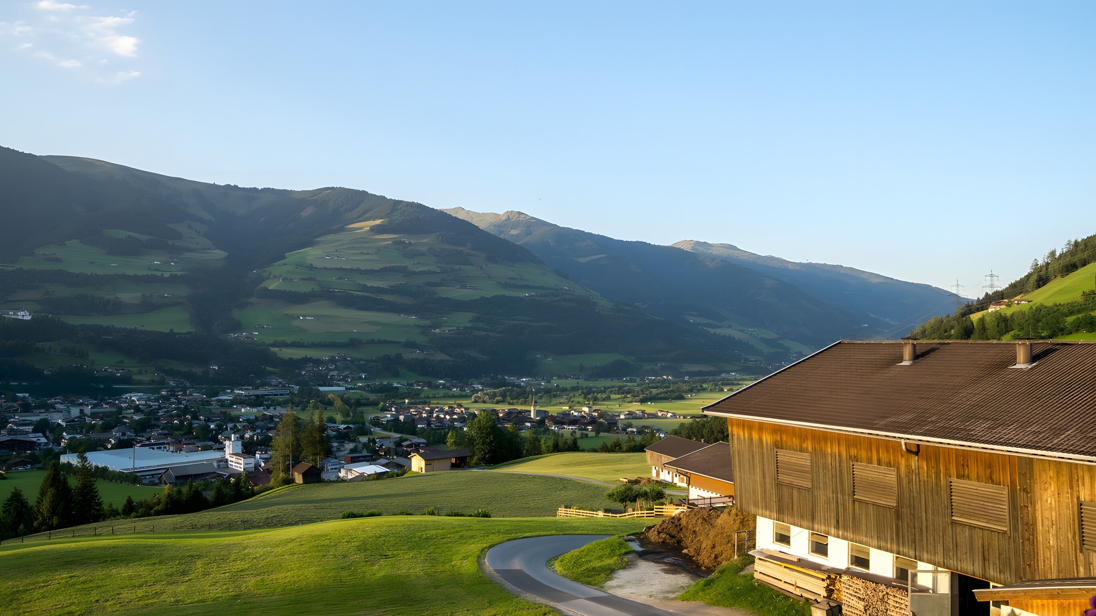Un paysage rural avec une route sinueuse, un bâtiment en bois et un village situé dans la vallée.