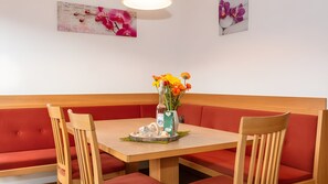 Ein Essbereich mit einem Holztisch, roten gepolsterten Bänken und einer Vase mit Blumen.