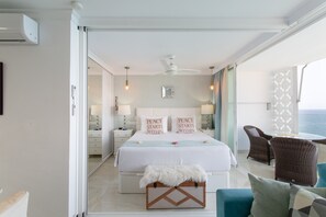 Une chambre à coucher avec un lit, des tables de chevet, un ventilateur de plafond et une vue sur l’océan.