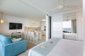 Una habitación de hotel moderna con una cama, un sofá, un escritorio y vista al océano.