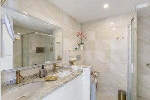 Un baño moderno con dos lavamanos, un espejo grande y una cabina de ducha de vidrio.