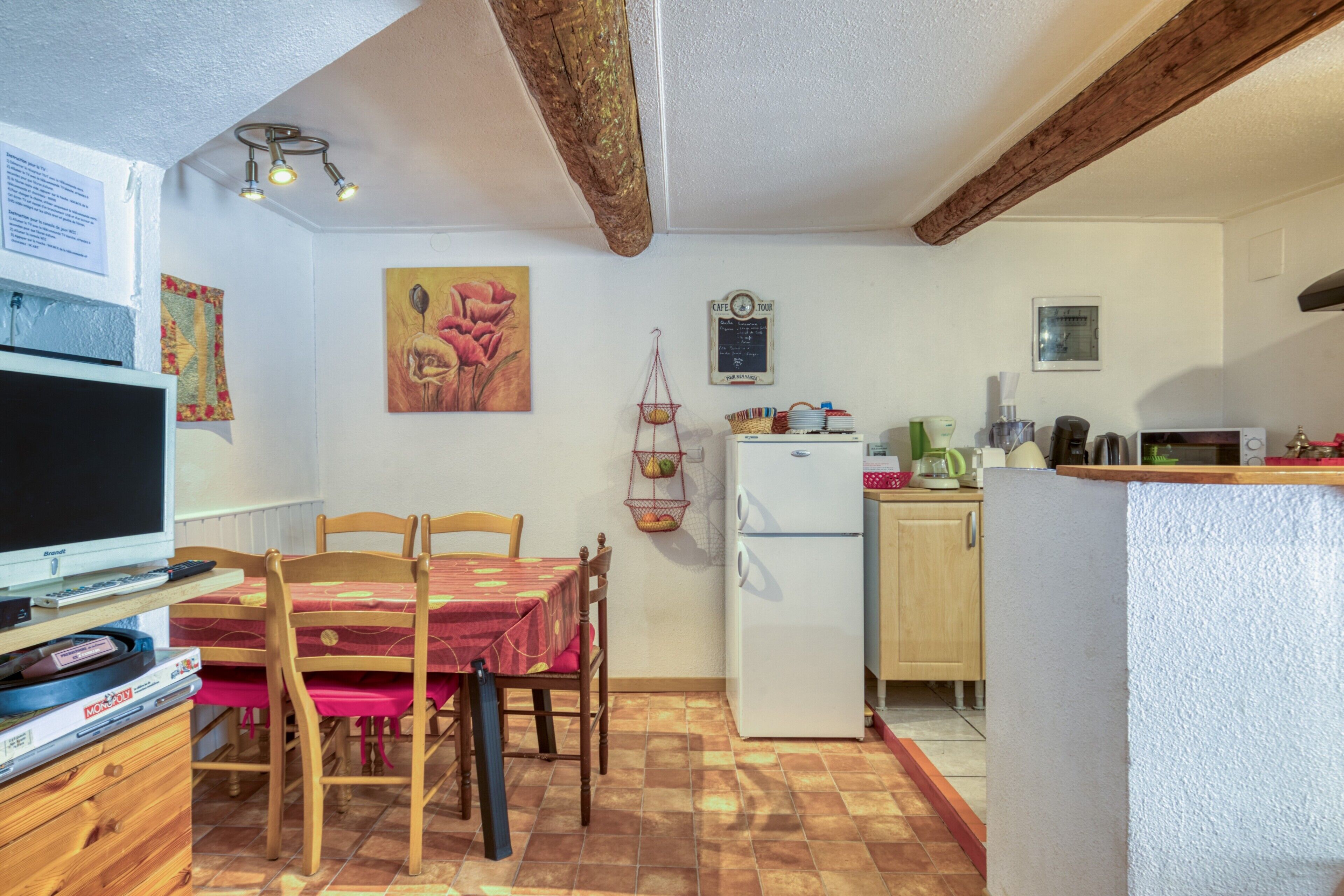 Eine kompakte Küche mit Kühlschrank, Mikrowelle und einer kleinen Essecke mit Stühlen und Tisch.