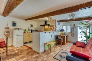 Een keuken met een centraal eiland, een eetgedeelte met een rode bank en uitzicht op de omgeving.