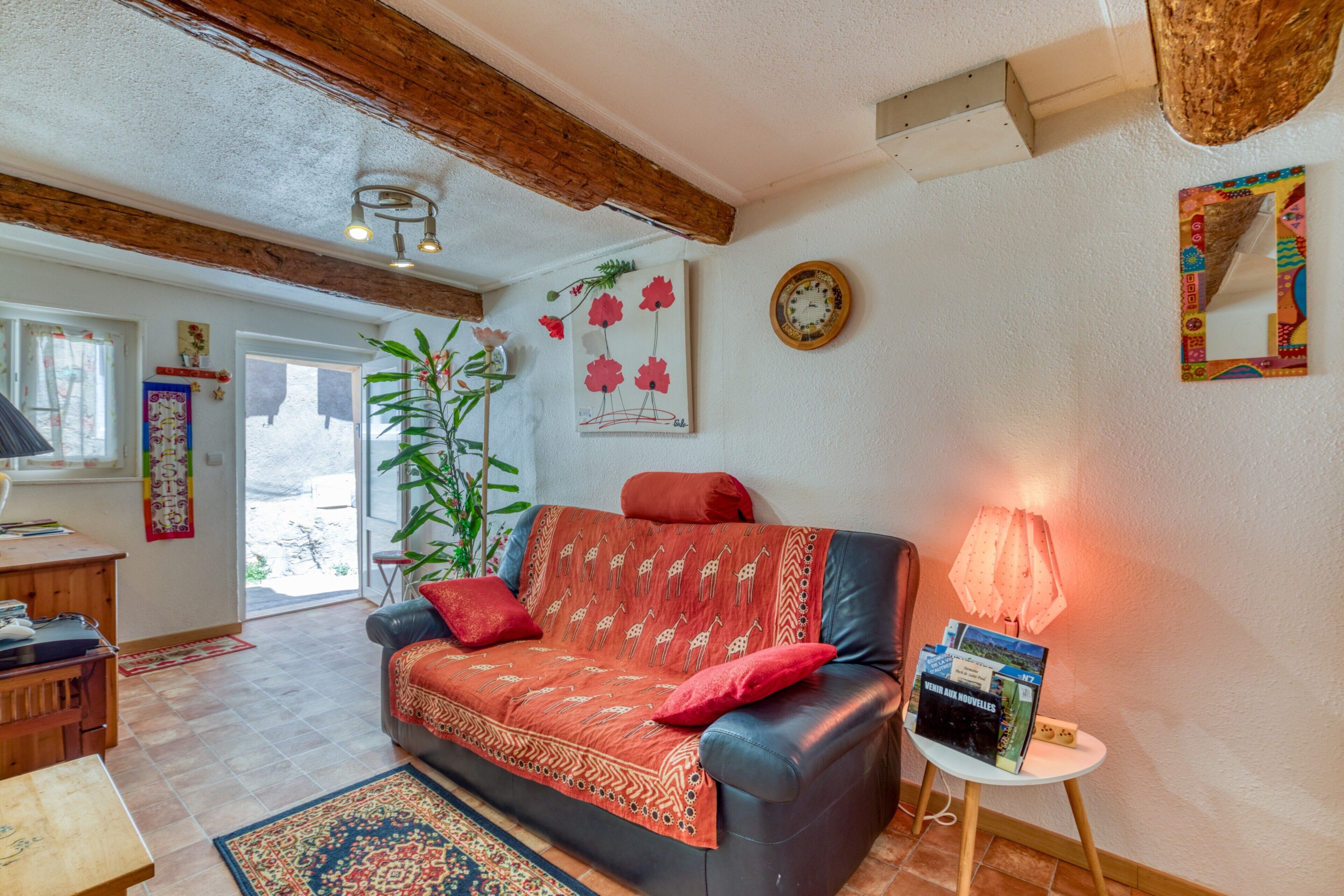 En stue med sofa, lampe, vægur og en plante.