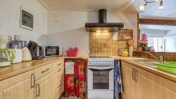 A kitchen with wooden cabinets, a stove, a sink, and a tiled backsplash.