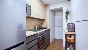Eine moderne Küche mit Edelstahlgeräten, Holzschränken und einer kleinen Arbeitsfläche mit Spüle.