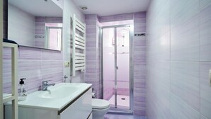 Ein modernes Badezimmer mit Waschbecken, Toilette und einer Duschkabine aus Glas.