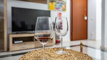 Dos copas de vino vacías sobre un mantel tejido en una habitación con una televisión y una puerta de madera al fondo.