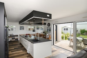 A modern kitchen with a central island, a dining area with outdoor seating, and a view of the garden. - Apartment 'Joli Nid Douillet Au Cœur Du Golfe' with Private Terrace, Private Garden and Wi-Fi (Baden)