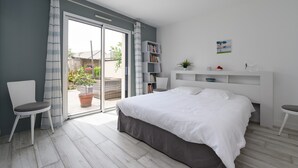 Ein Schlafzimmer mit einem Bett, einem Sessel, einem Bücherregal und Blick ins Freie.