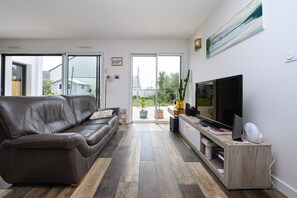 A modern living room with a leather sofa, a TV, and a wooden desk. - Apartment 'Joli Nid Douillet Au Cœur Du Golfe' with Private Terrace, Private Garden and Wi-Fi (Baden)