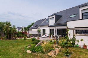 Una hilera de casas modernas con techos inclinados, un patio con césped y plantas en macetas.