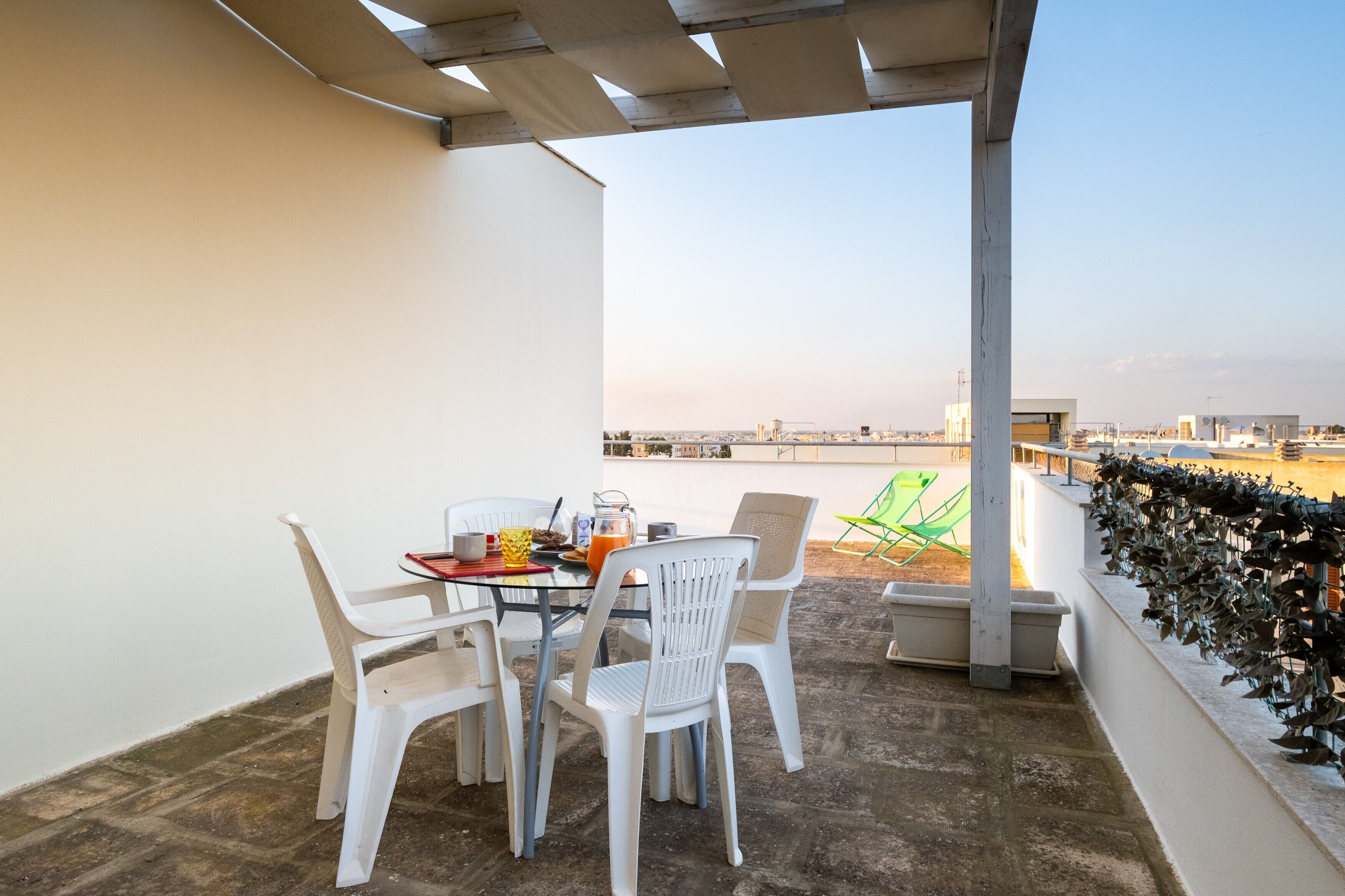 A terrace with a table and chairs, a view of the city, and a decorative plant wall.