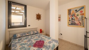 Ein Schlafzimmer mit Bett, Fenster, Wandbild und Deckenventilator.