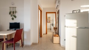 Eine moderne Küche mit Kühlschrank, einem Esstisch mit Stühlen, einem Fernseher und einer dekorativen Wand mit Pflanzen.