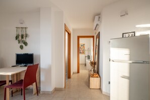 Eine moderne Küche mit Kühlschrank, einem Esstisch mit Stühlen, einem Fernseher und einer dekorativen Wand mit Pflanzen.