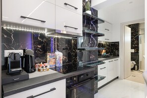 Eine moderne Küche mit schwarzem Marmorfliesenspiegel, Edelstahlgeräten und einem Ofen mit Glasfront.