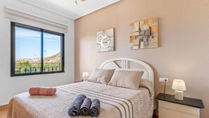 Quarto com cama, mesa de cabeceira, luminária e obra de arte na parede.