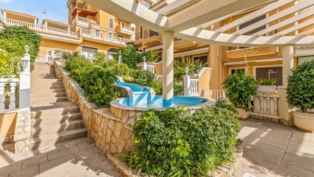 Um pátio com piscina, degraus de pedra e uma pérgola.