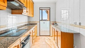 Uma cozinha com armários de madeira, um exaustor de aço inoxidável, forno duplo e painel de vidro.