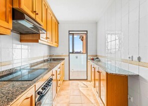 A kitchen with wooden cabinets, a stainless steel range hood, a double oven, and a glass backsplash. - Your refuge in front of the sea, in Santa Pola, bright apartment with swimming pool (Santa Pola)