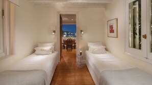 Una habitación con dos camas, piso de madera, una mesa con sillas y vistas de la ciudad de noche.