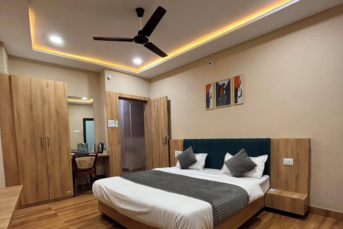 Un dormitorio con cama, armario de madera, ventilador de techo y una obra de arte en la pared.