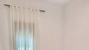 Makuuhuoneessa on sänky, kaksi yöpöytää, ikkuna, jossa on ohuet verhot, ja näkymä merelle.